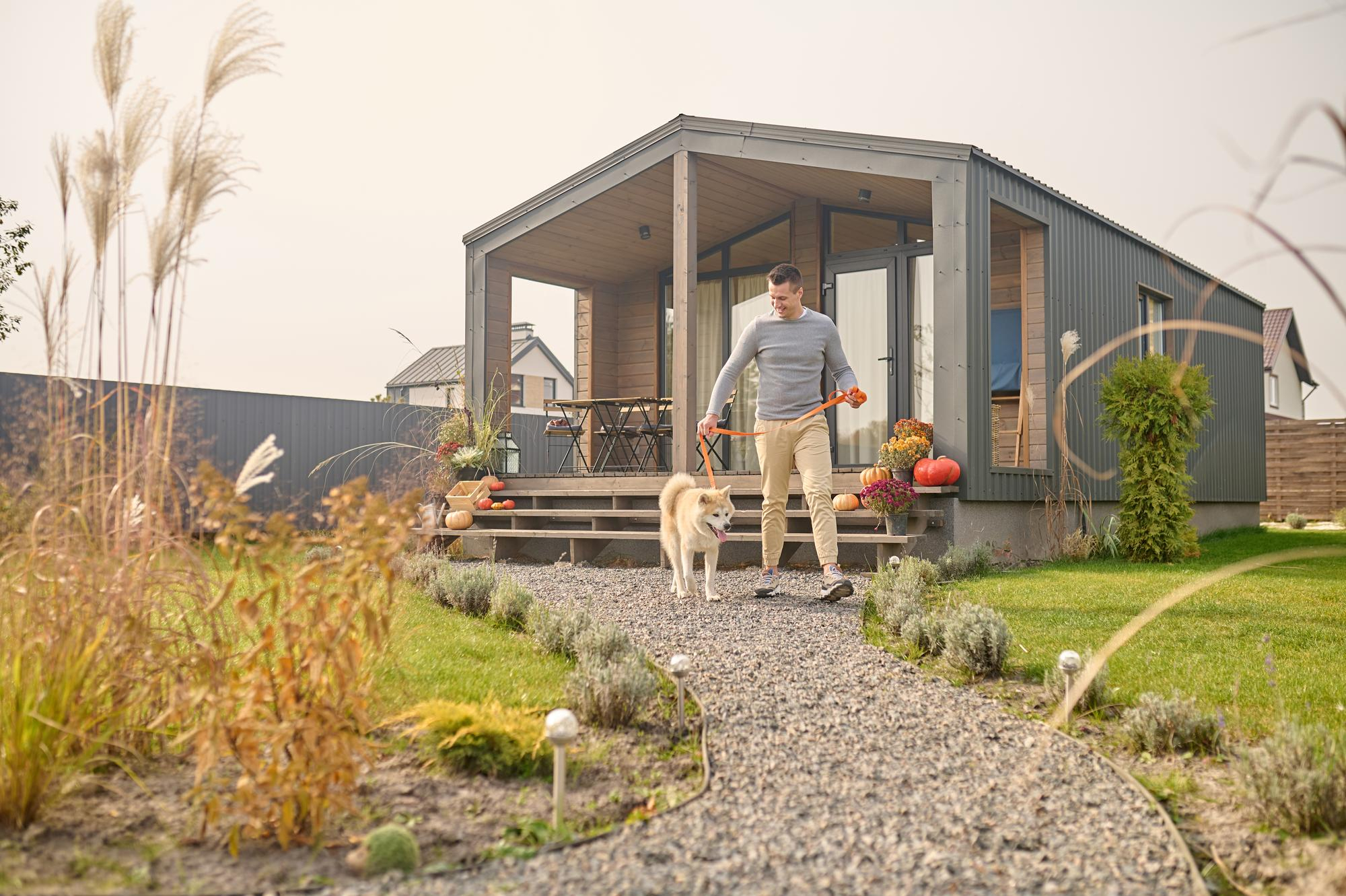 How to Add Plumbing to a Shed, Workshop or ADU in Greenville & Upstate SC - man leaving a nice metal ADU in a home backyard with his dog